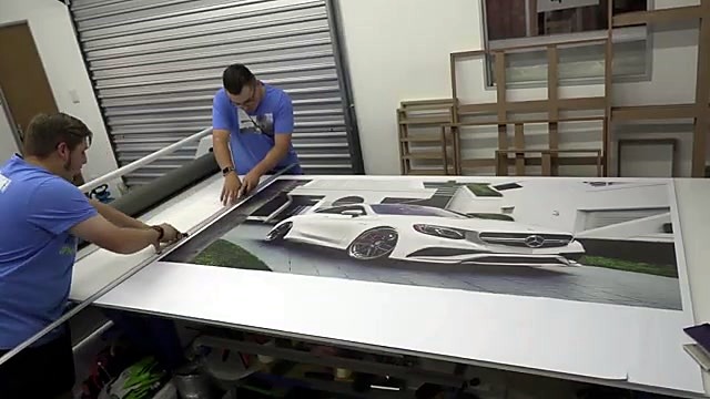 Technicians aligning printed Mercedes banner on finishing table (SKU ask)