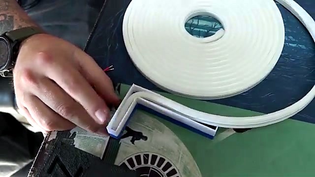 Hands insert white LED neon flex into printed channel (SKU ask)