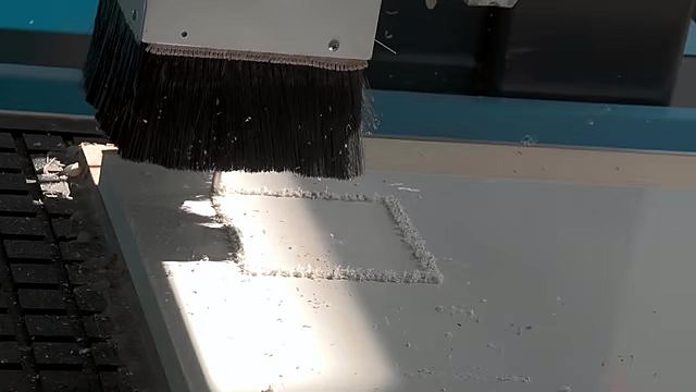 Brush-shroud spindle cutting square pocket in white PVC foam (SKU ask)