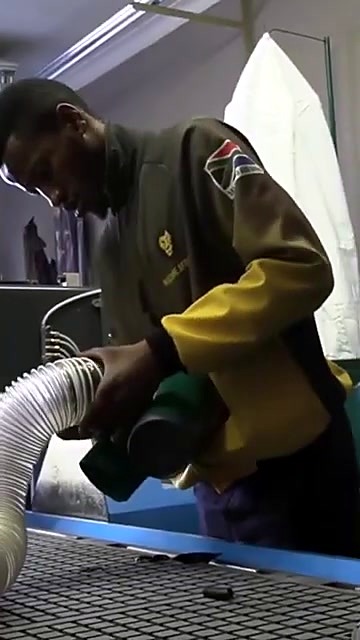 Operator in AM jacket vacuum-cleans bed (SKU ask)