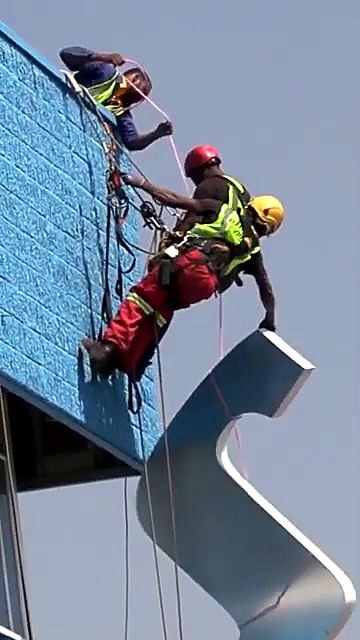 Rope-access techs mounting letter on blue facade (SKU ask)