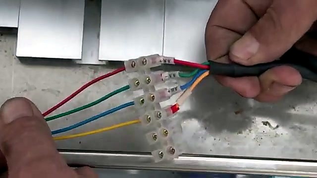 Hands wiring coloured leads into terminal block (SKU ask)