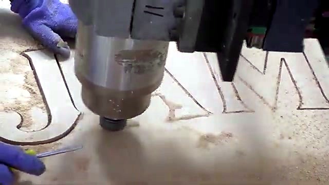 Blue gloves clearing chips from carved letter pockets (SKU ask)