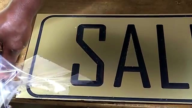 Hand peeling protective film from finished SALES sign (SKU ask)