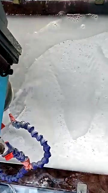 Close view of the stone router spindle carving the elephant relief under running coolant