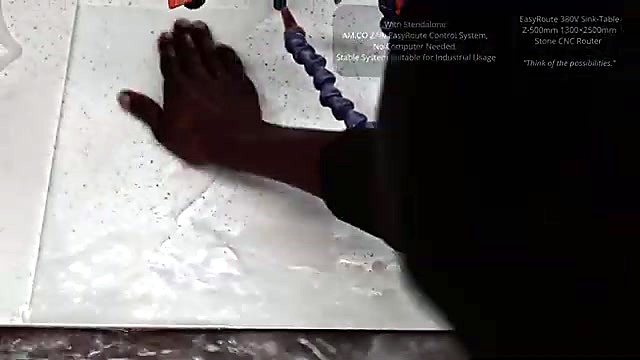 Hand feeling the freshly carved elephant relief on the wet marble slab on the stone router bed