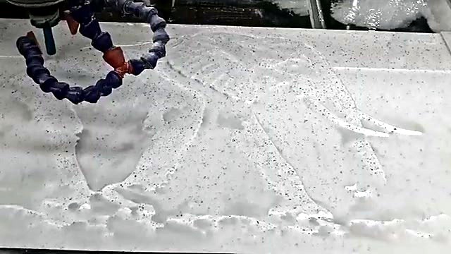 EasyRoute stone CNC router spindle with blue coolant hoses carving the elephant outline into marble