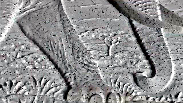 Close-up of the elephant head and tusk relief carved into speckled marble