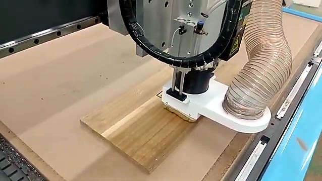 Spindle with white dust hood and hose over the wood board