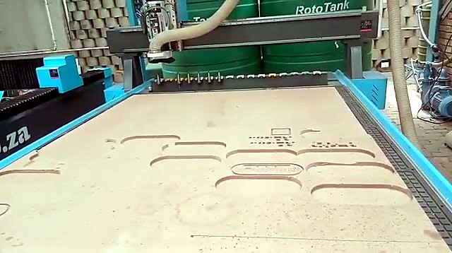 Full EasyRouter vacuum bed with routed obround pockets and marked text on a wood sheet