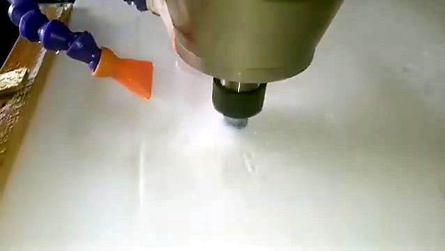 Water-cooled spindle with orange coolant nozzles cutting into white quartz stone