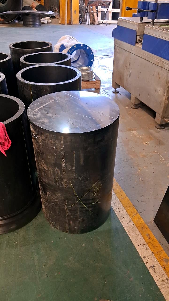 R-2030K/55L EasyRoute: large black plastic pipe sections fitted with CNC-cut end caps on the factory floor (application, staff still)