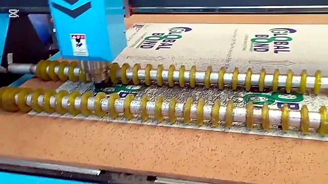 Fixed spindle + yellow rollers mid-cut; black swarf on sheet (SKU ask)