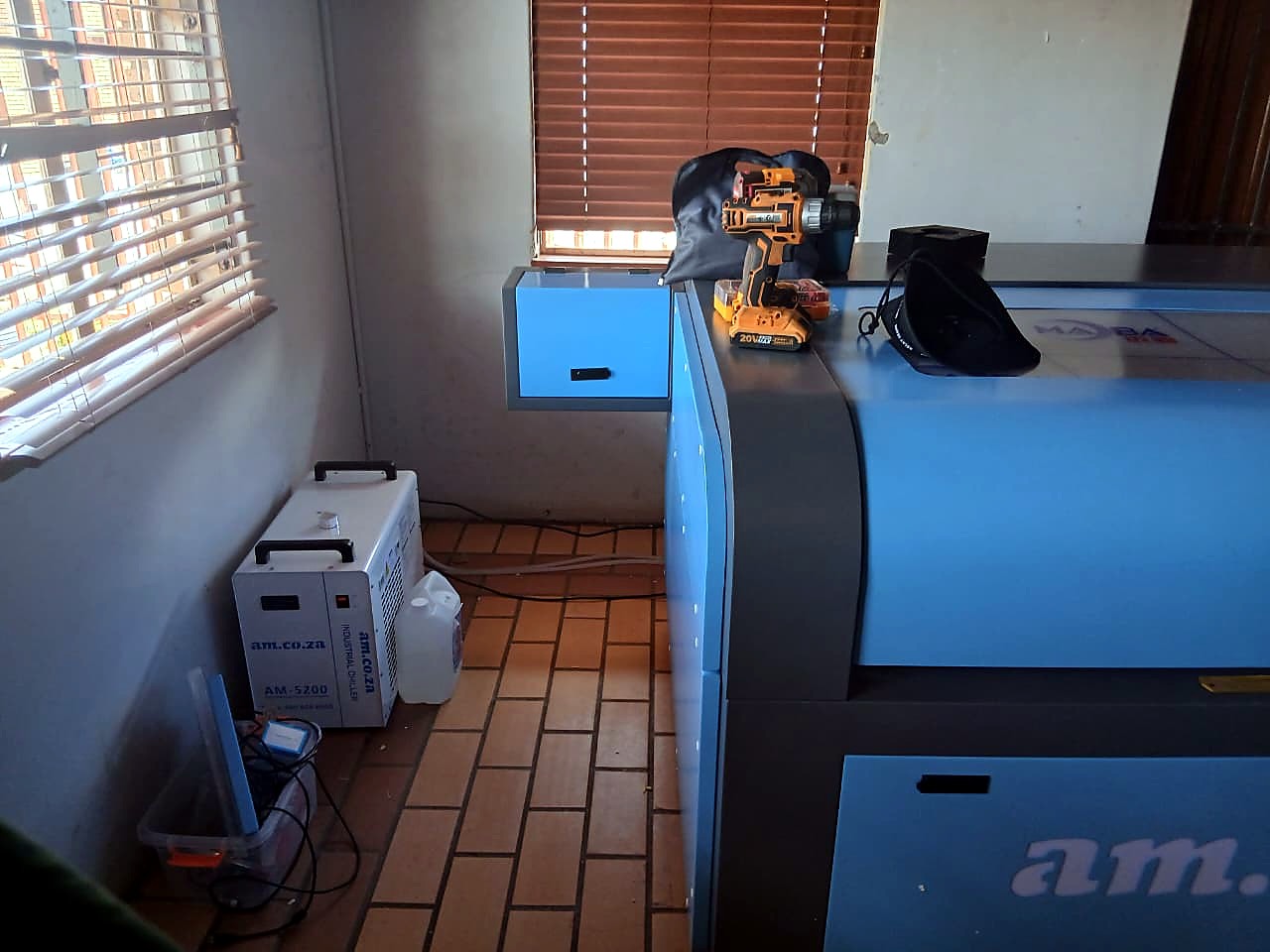LC-1390/150: blue am.co.za cabinet CO2 laser seen from the side with the CW water chiller alongside (staff still)