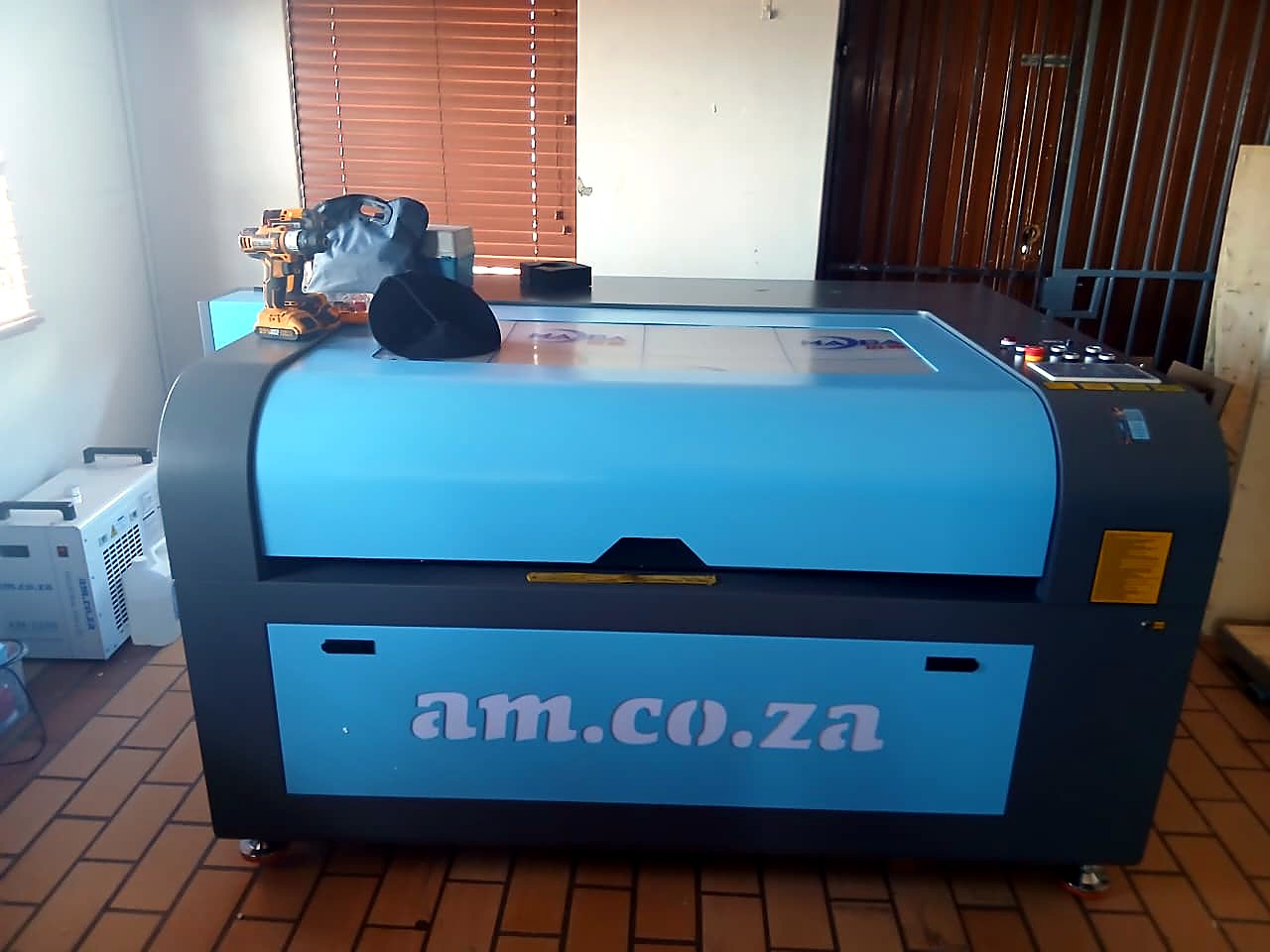 LC-1390/150: front view of the blue/grey cabinet CO2 laser with am.co.za branding on the front panel (staff still)