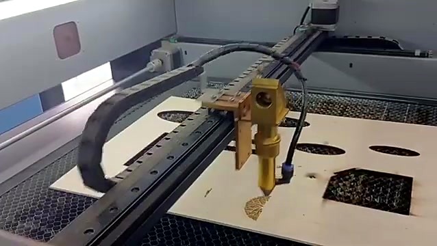 Laser head beginning to engrave a round tree motif on basswood