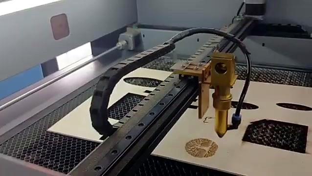 Gantry with cable chain and gold laser head engraving the round tree design