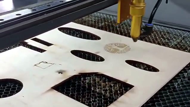 Finished round tree engraving on basswood beside the laser head