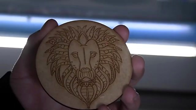 Finished circular wooden lion-head coaster held up (SKU ask)