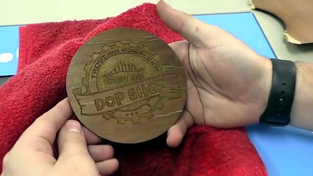 Finished deep-engraved DOP SHOP wooden coaster held up (SKU ask)