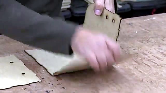 Hands bending living-hinge roof during assembly (SKU ask)