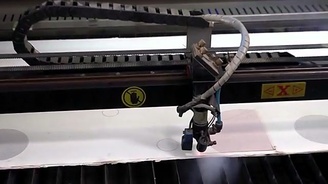 Laser head cutting UV-printed circular graphics on Perspex (SKU ask)