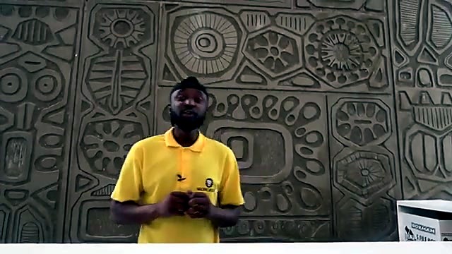 Presenter yellow AM.CO.ZA polo before patterned wall (SKU ask)