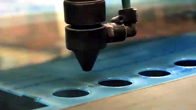 Laser nozzle cutting circular grid on blue-masked plexiglas (SKU ask)