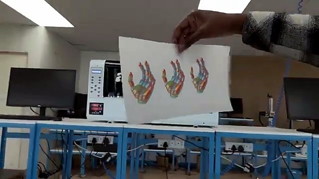 Hand holding colourful DTF print sheet in workshop (SKU ask)