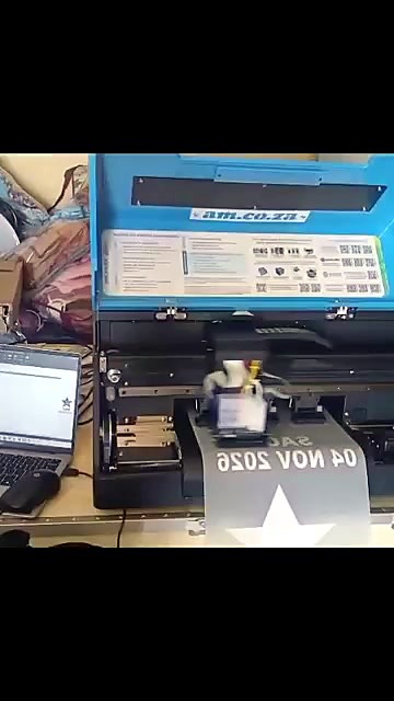 F-DTF/A3 DTF printer with blue lid printing white lettering and a star on DTF film, laptop beside it