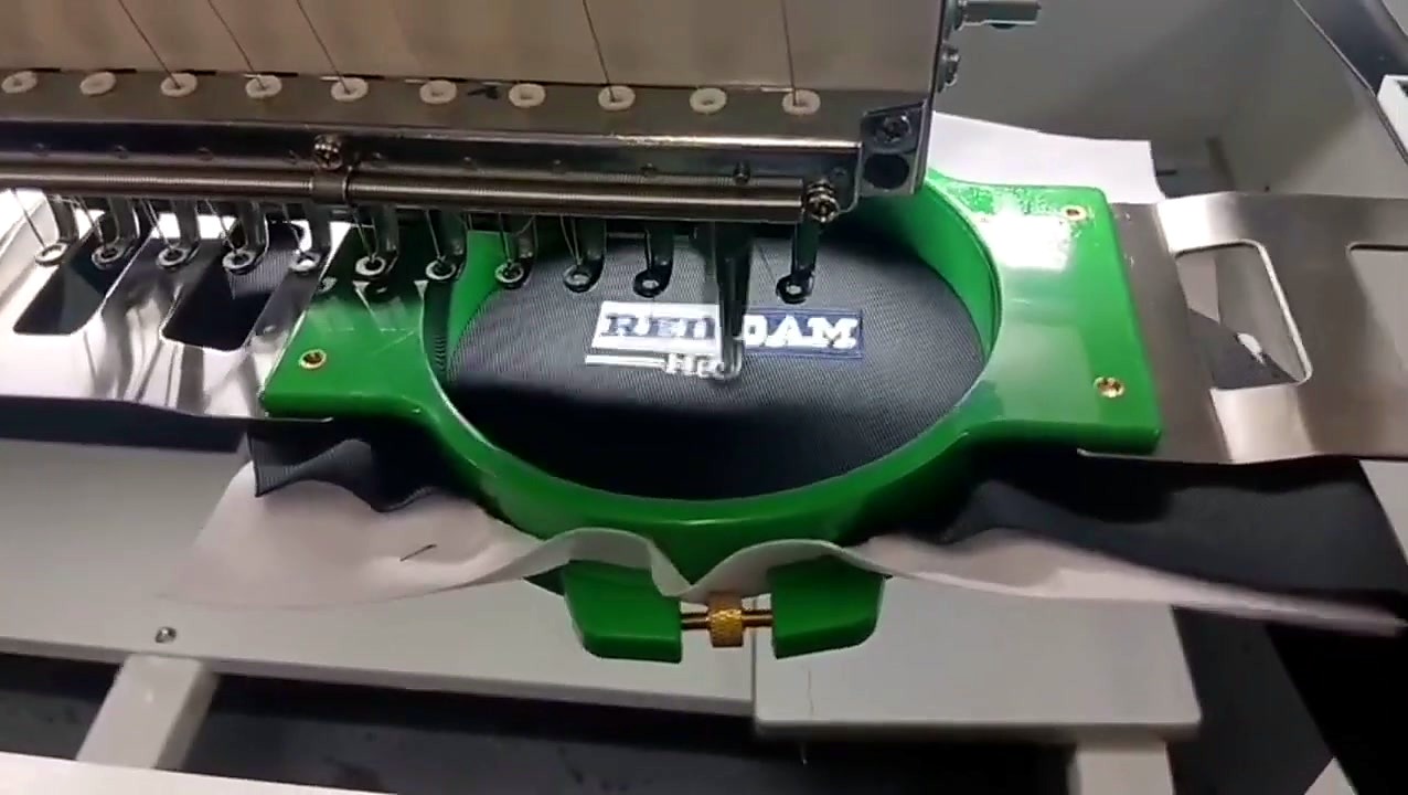 Needle over embroidered logo progress in green hoop (SKU ask)