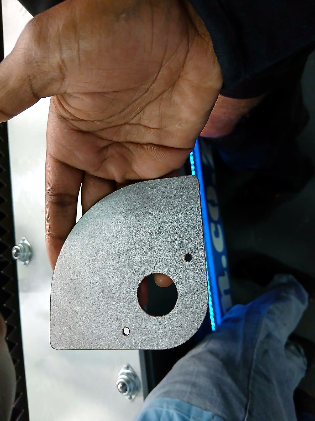 LF-2040/12000 RayCUT: hand-held metal cut sample (center hole + rounded corner) near branding panel (April product still)