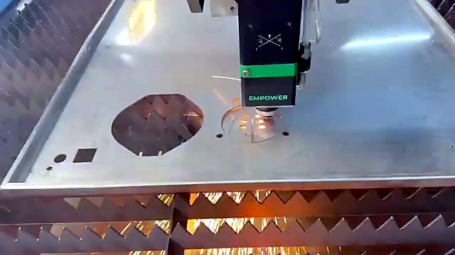 Fiber laser head tracing a cut beside octagonal and square cut-outs in the steel sheet