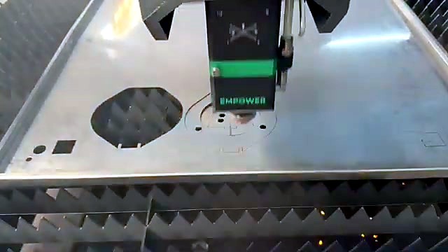 Steel sheet with an octagonal cut-out, small square holes and fresh cut paths under the cutting head