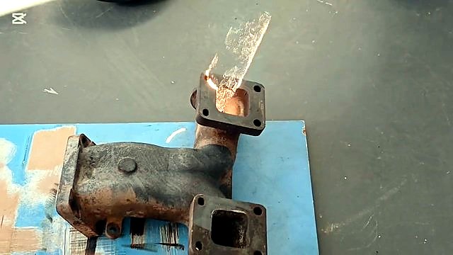 Handheld gun cleaning rusty manifold flange with sparks (SKU ask)