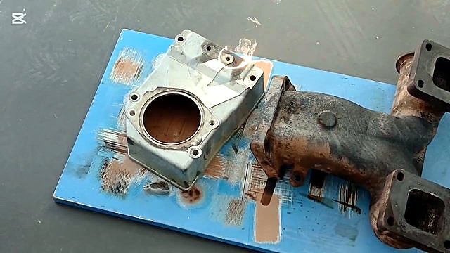 Manifold + aluminium casting on blue board mid-clean (SKU ask)