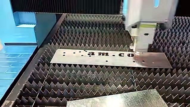 am.co letters spark-cut into metal under laser head (SKU ask)