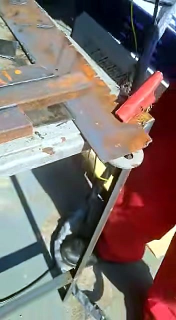 Rusted bars in red clamps; handheld unit umbilical visible (SKU ask)