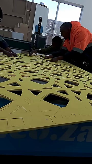 Operators lift finished yellow foam lattice from FlatCUT (SKU ask)