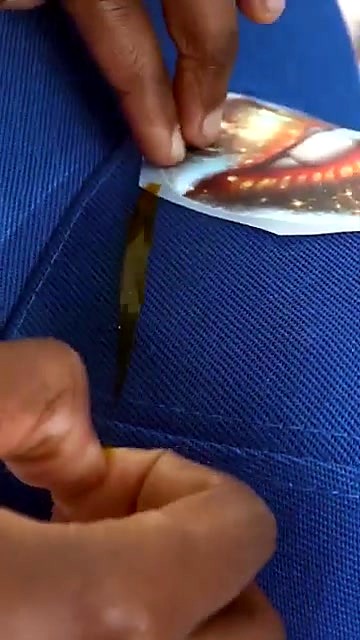 Hands applying transfer on blue cap (SKU ask)