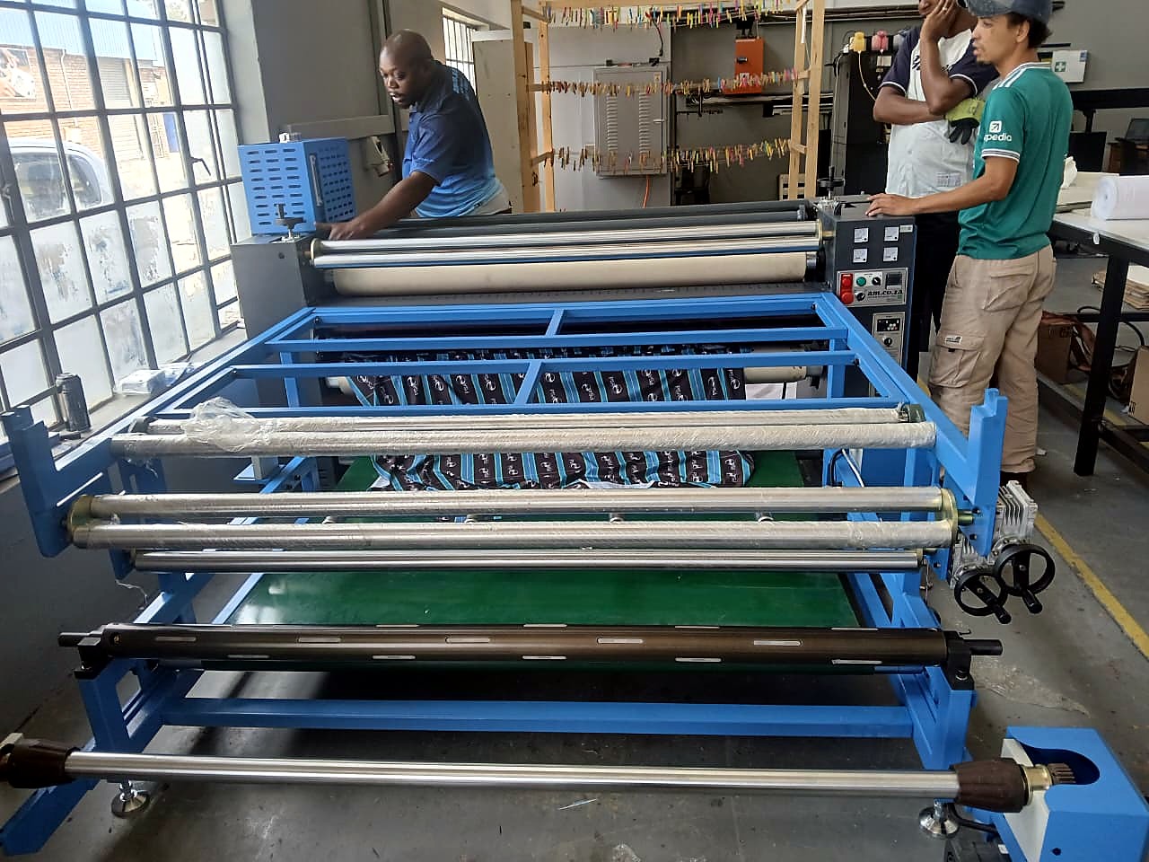 H-ROLLER/1700/OIL9: workshop overview — tech adjusting rollers with patterned fabric loaded (staff still)
