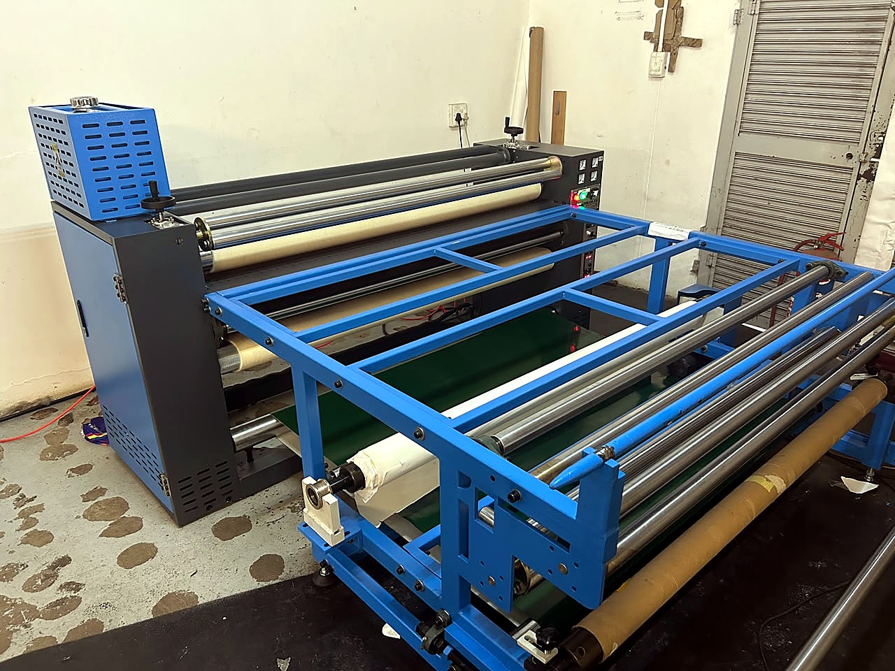 H-ROLLER/1700/OIL9: 1700mm oil-heated roller heat press - grey/blue cabinet with control panel, felt blanket over the heated drum, and blue front feed/take-up roller frame with paper and tissue rolls (staff still)