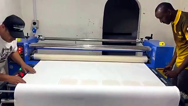 Operators feeding fabric into blue oil roller (SKU ask)