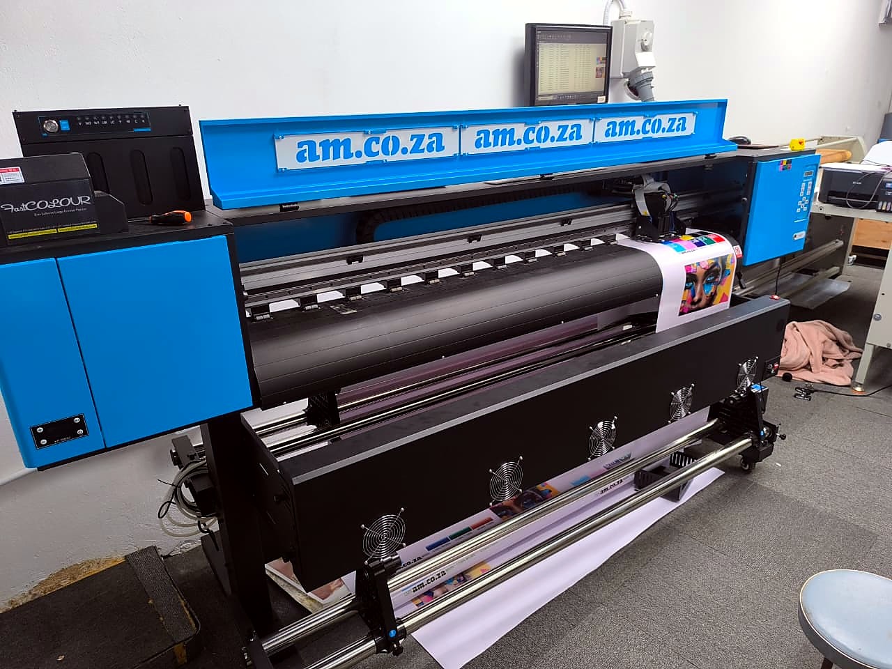 F2-1800 FastCOLOUR ONE: blue/black am.co.za-branded 1.8m printer on stand in showroom, media loaded with take-up (staff still)