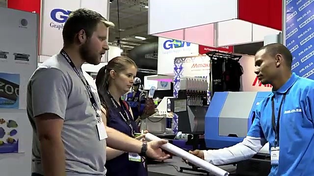 Staff handoff rolled sample at am.co.za booth (SKU ask)