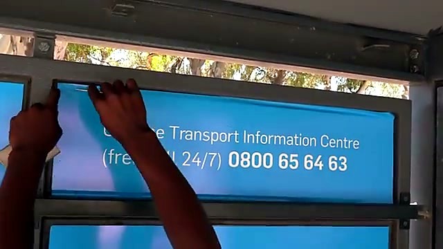 Technicians squeegee-applying MyCiTi vinyl on bus shelter (SKU ask)