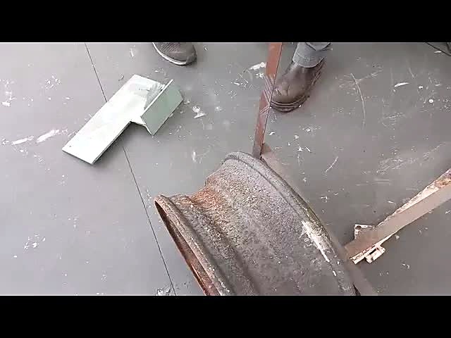 Rusty steel wheel rim and paint-off test plate on the workshop floor after LM-V/3000 laser cleaning
