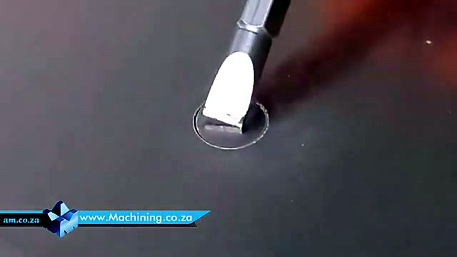Screwdriver pushing cut slug through grey sheet (SKU ask)