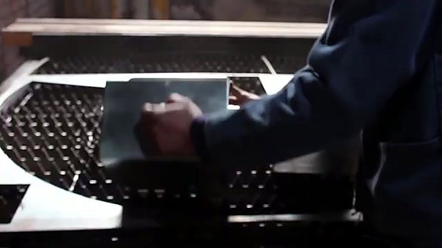 Operator lifting finished rectangular steel part from bed (SKU ask)