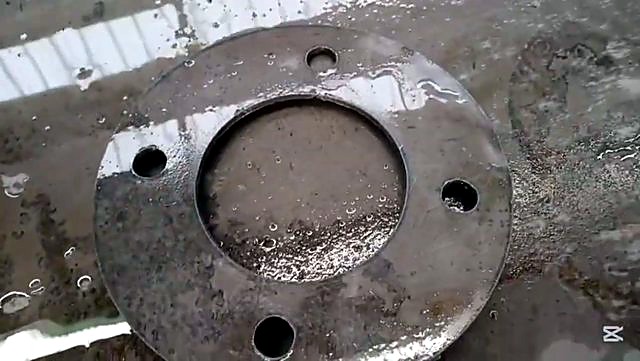 Finished plasma-cut circular flange with 4 bolt holes on wet bed (SKU ask)